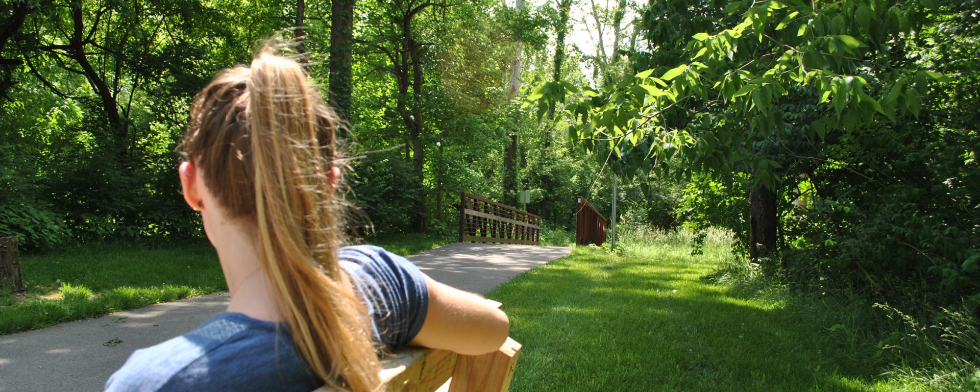 girl on bench by park trail