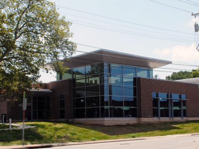 brick library building with big windows and a tree out front